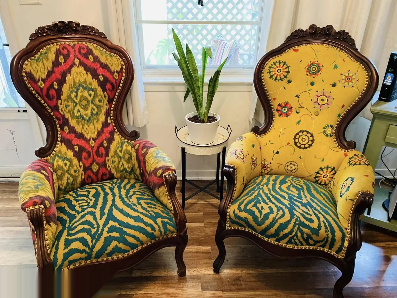 Matching pair of wingback chairs reupholstered in bold red, yellow, and green floral fabric.