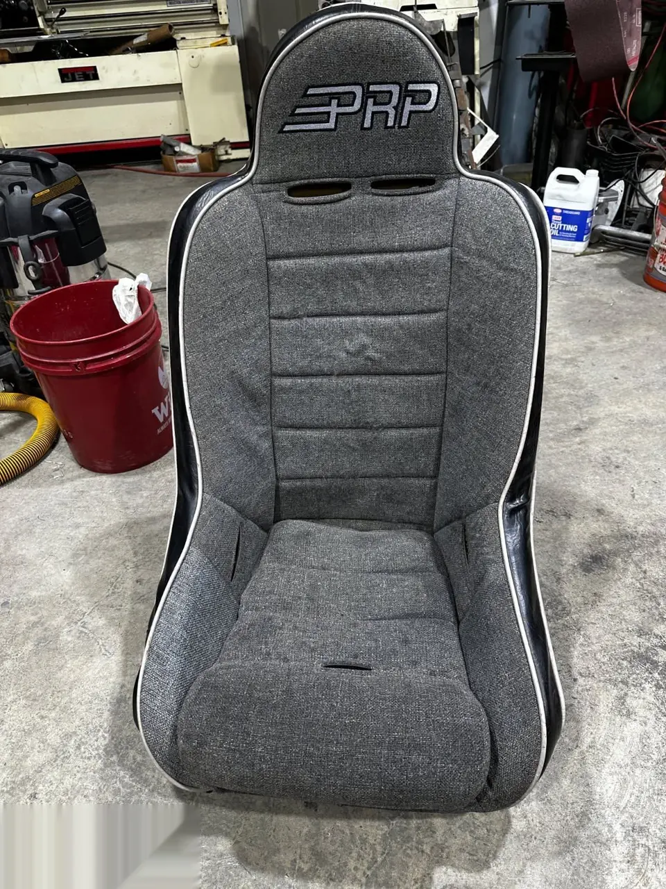 Worn gray suede racing bucket seat before restoration.