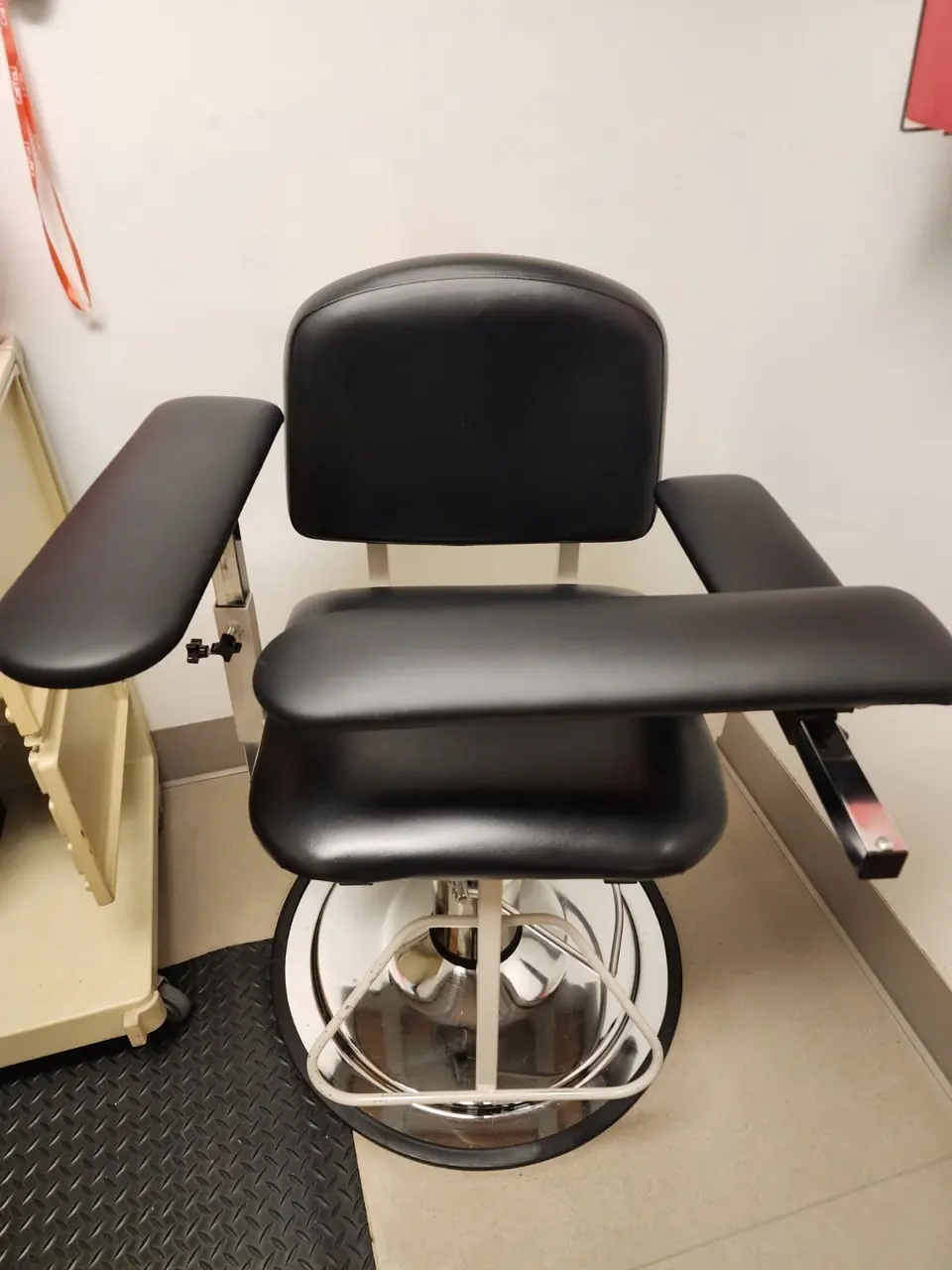 Black vinyl medical treatment chair reupholstered for a physical therapy clinic.