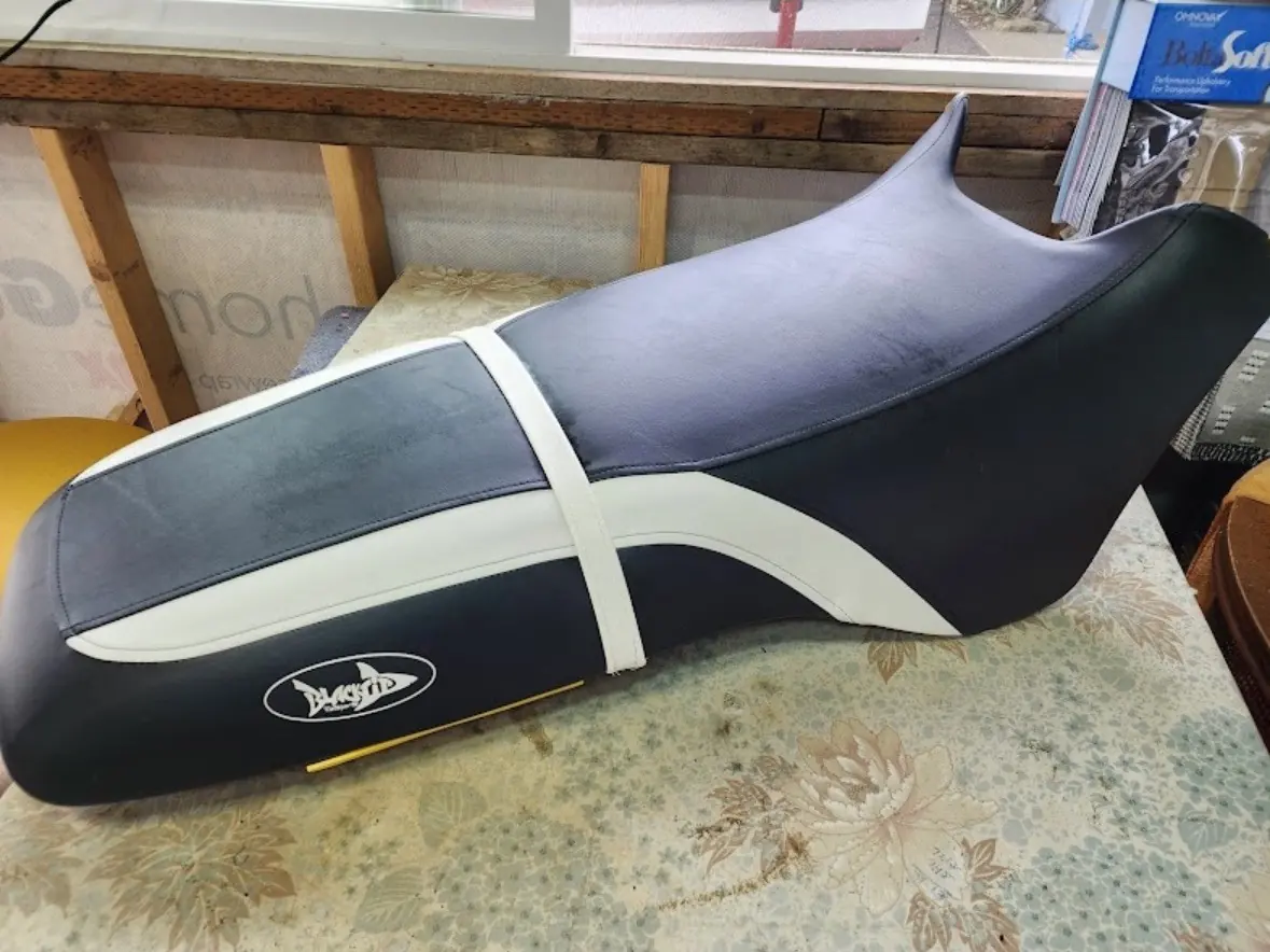 Personal watercraft seat reupholstered in black, gray, and white marine vinyl with logo detail.