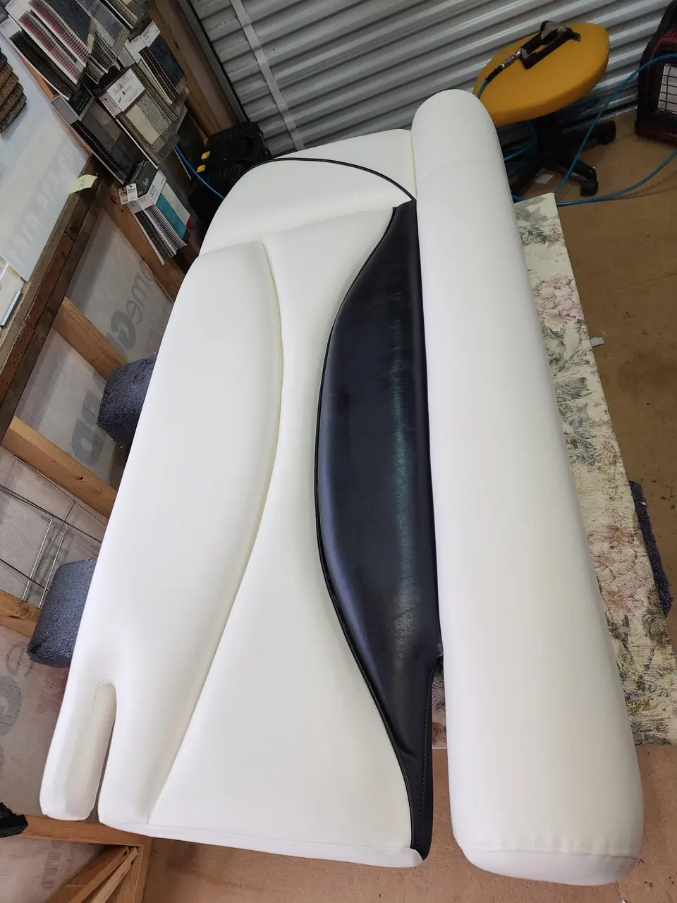 Boat bow seating reupholstered in white marine vinyl with a black accent panel.