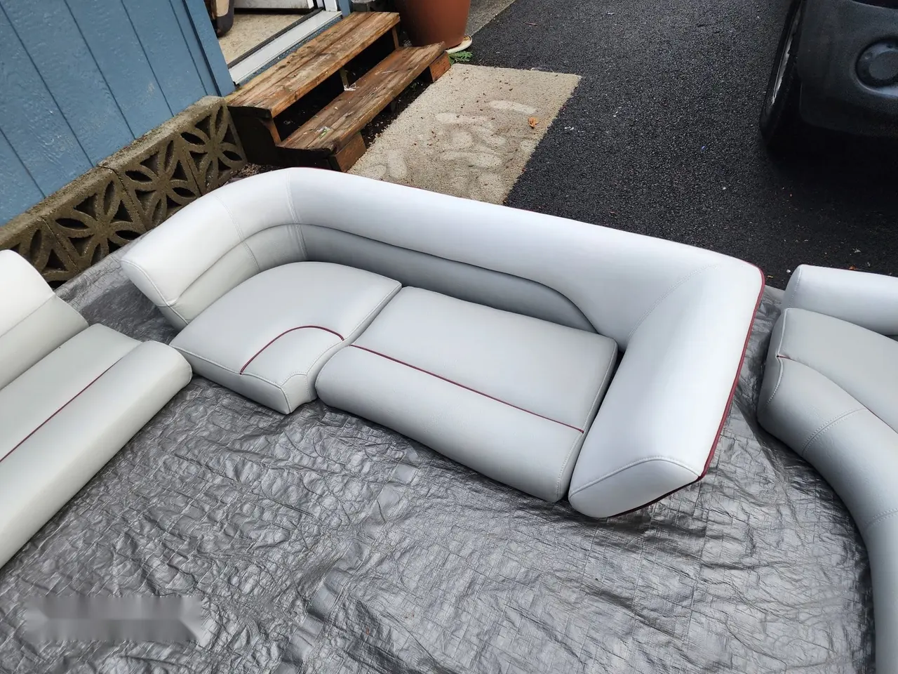 Pontoon boat seating set reupholstered in light gray marine vinyl with maroon piping.