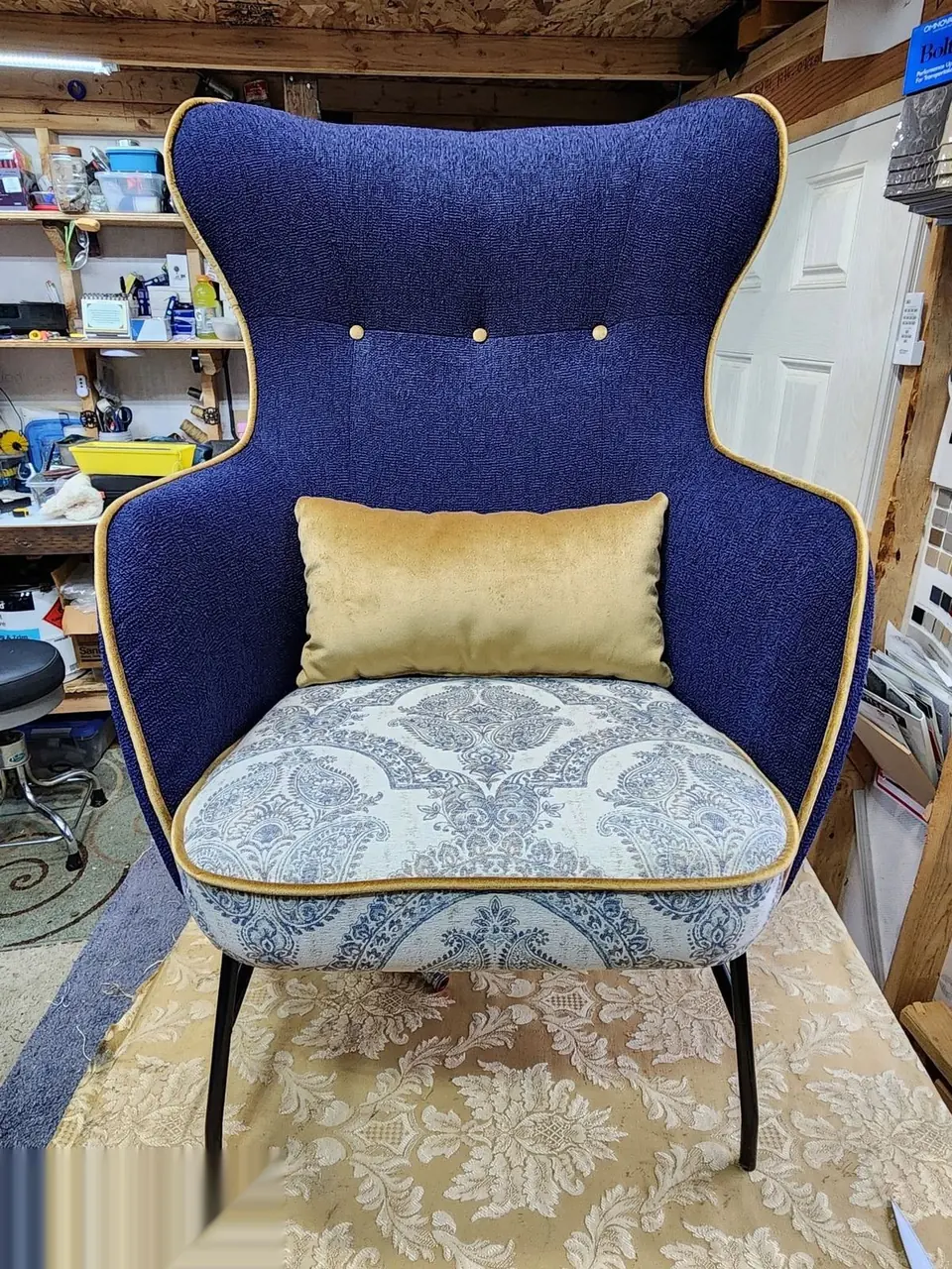 Wingback chair reupholstered in blue fabric with a gold accent pillow.