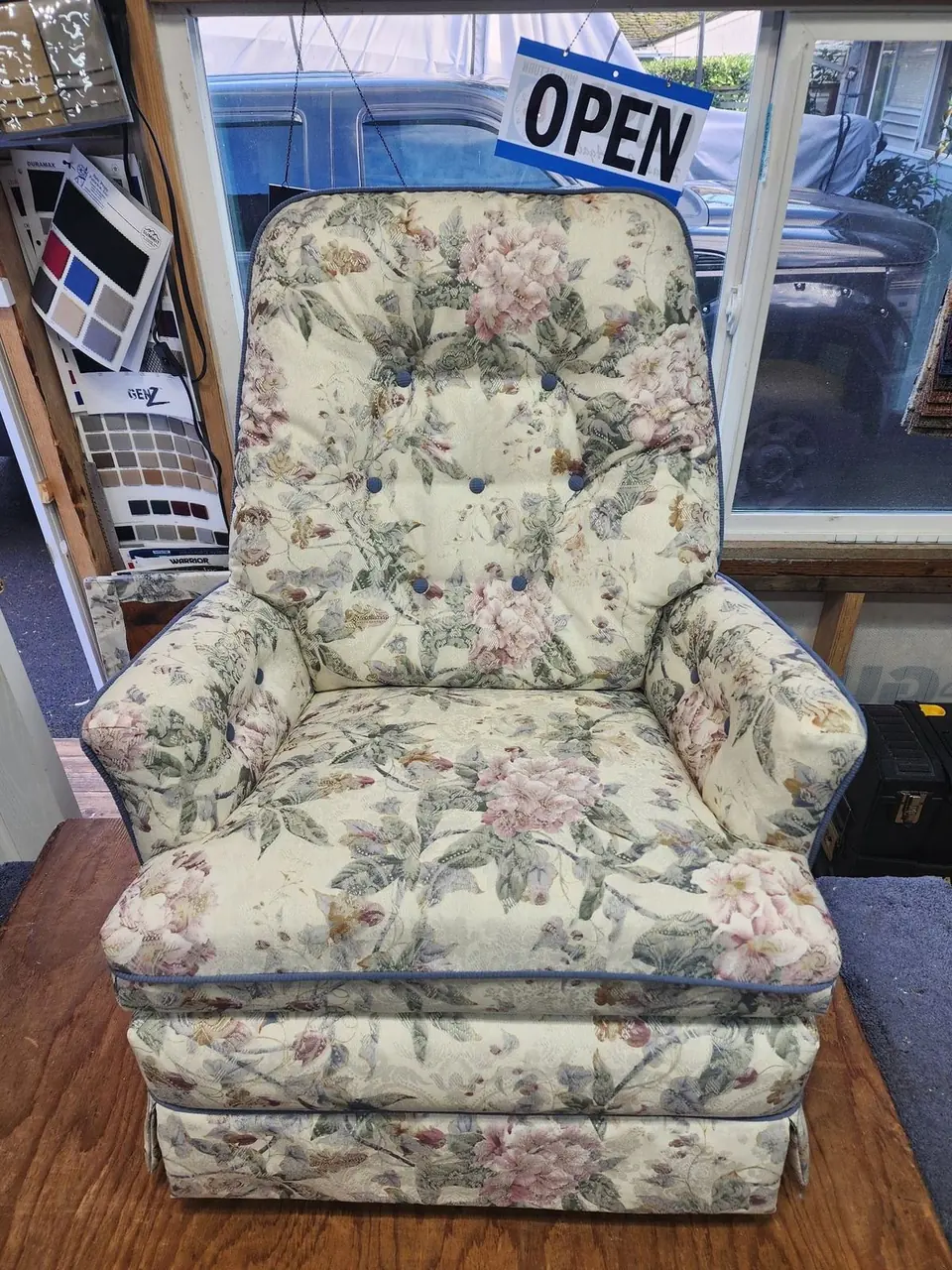 Rocker-recliner reupholstered in a cream floral fabric, recliner mechanism visible.