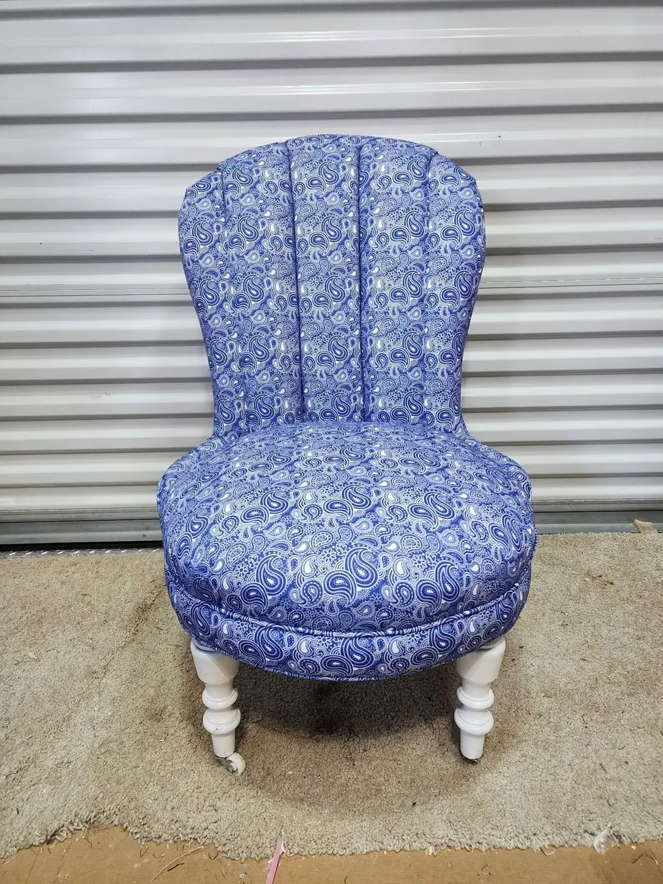 Small boudoir chair reupholstered in a blue and white paisley print, on turned white legs.