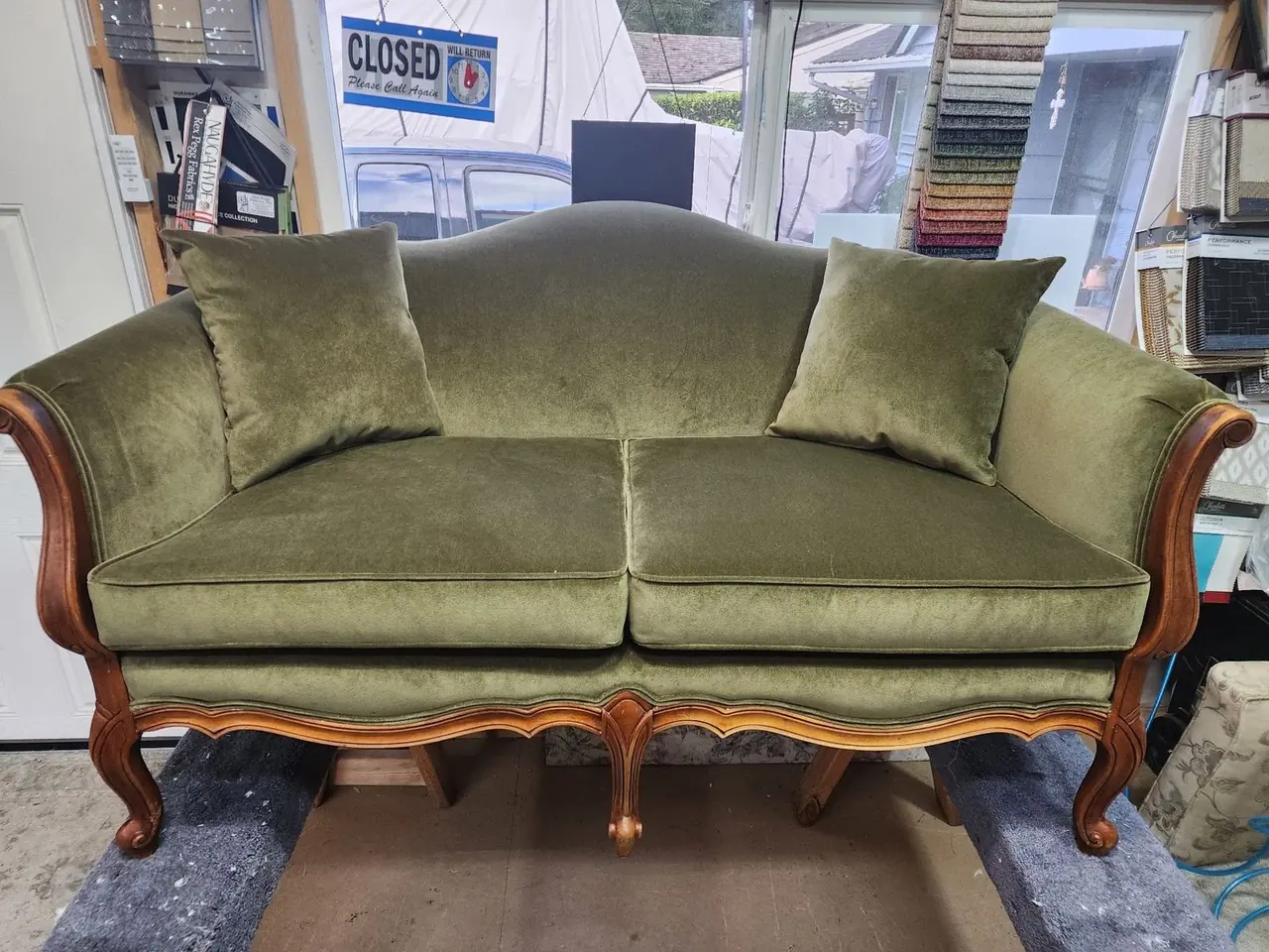 Carved-wood loveseat reupholstered in olive green velvet with matching pillows.