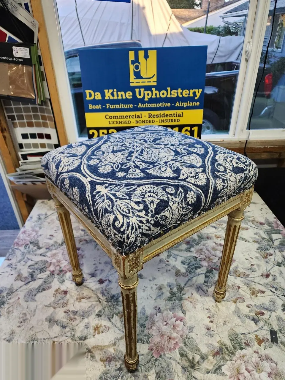 Small vanity bench reupholstered in navy and cream damask fabric, gold-accented legs.
