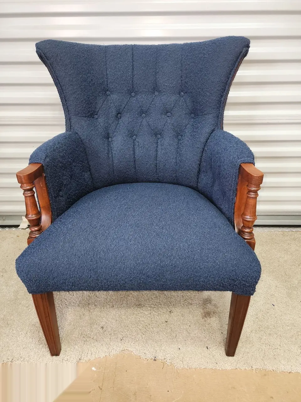 Antique wingback chair reupholstered in navy channel-tufted fabric.