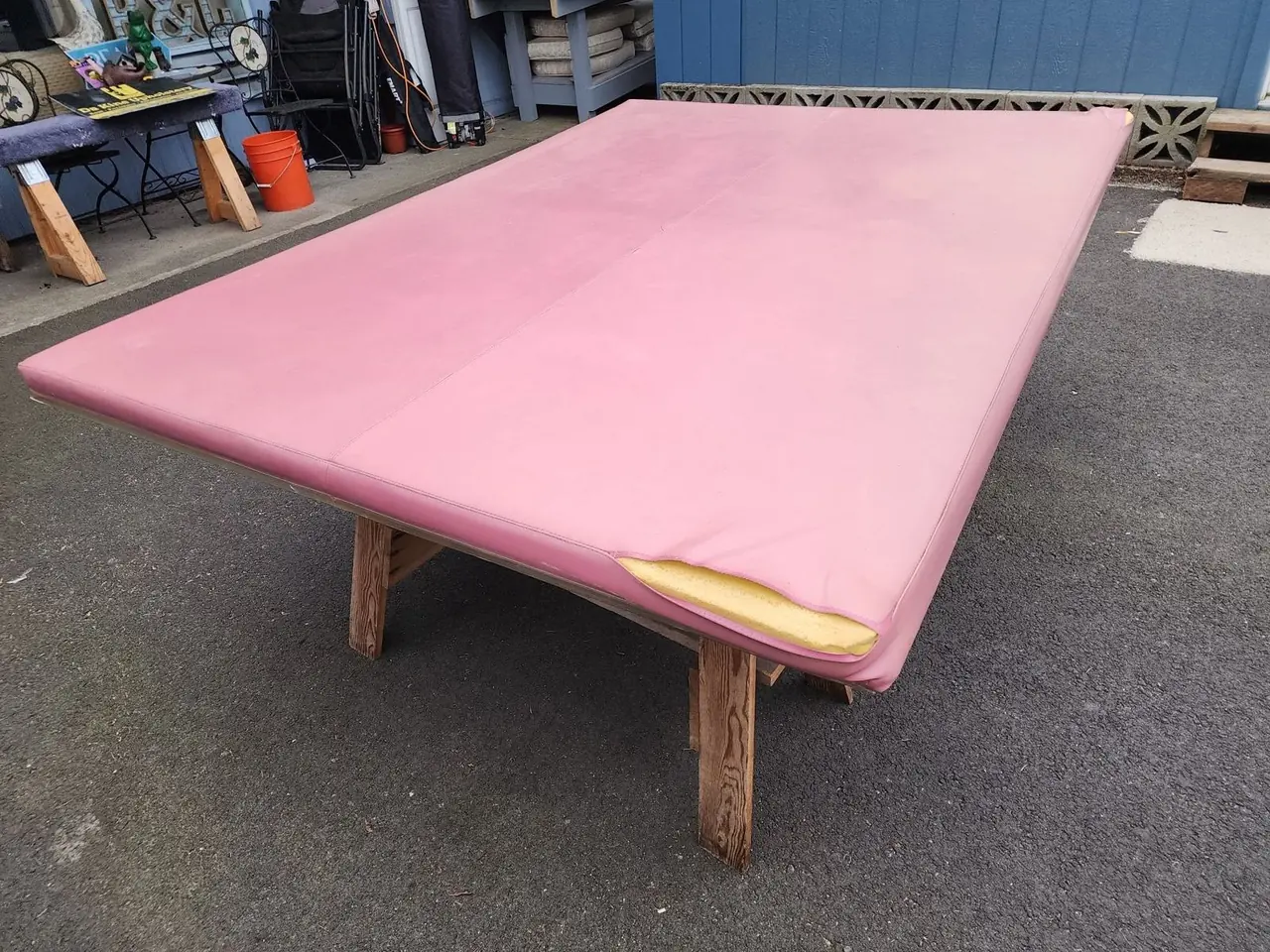 Detail of a physical therapy treatment table with a torn pink vinyl top before restoration.