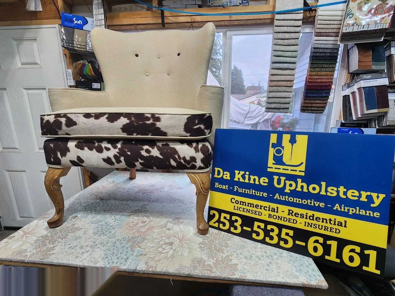 Cream tufted chair paired with a cowhide-print ottoman, staged with the shop sign.