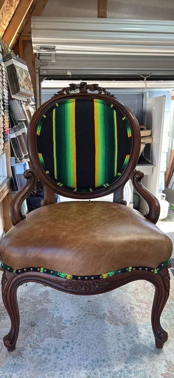 Antique carved wood chair reupholstered in a bold green, black, and gold striped fabric with a tan leather seat.