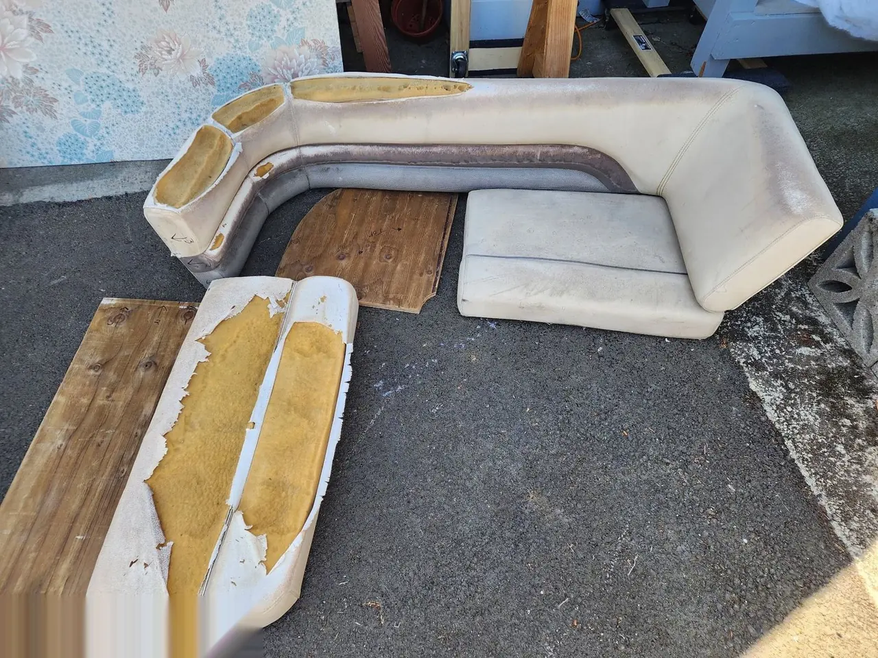 Boat bench cushions removed and torn apart on a table before restoration.