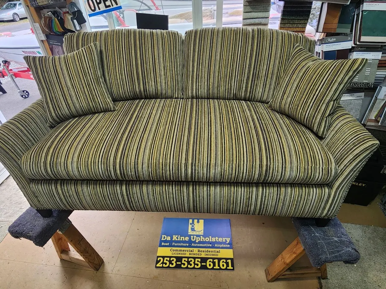 Sofa reupholstered in a bold yellow, black, and cream stripe, staged in the shop.