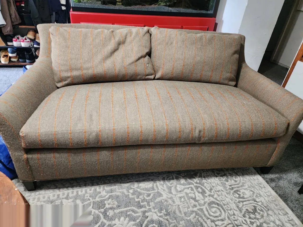 Loveseat in a worn tan and orange pinstripe fabric before restoration.