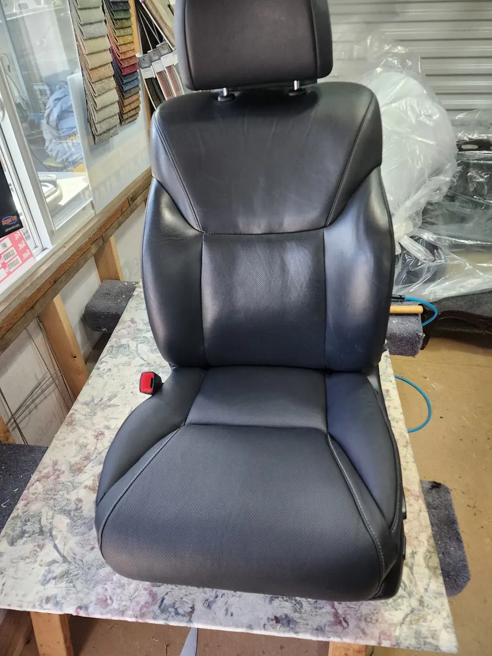 Automotive bucket seat reupholstered in black leather.