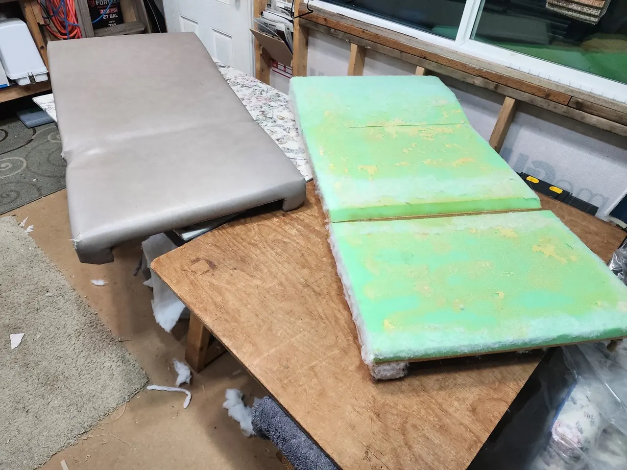 Finished gray vinyl commercial bench cushion next to fresh replacement foam padding.