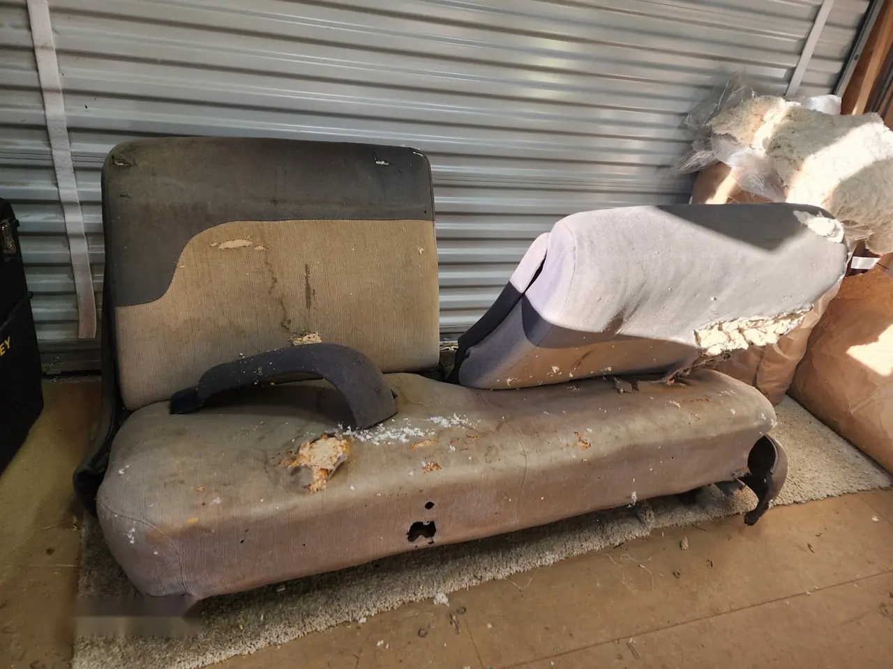 Worn and torn brown truck bench seat before restoration, foam and springs exposed.