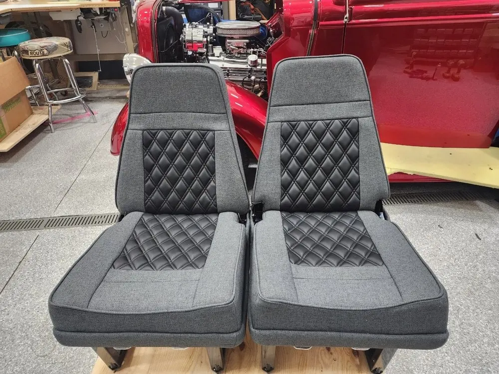 Pair of aircraft seats reupholstered in charcoal fabric with black quilted vinyl inserts.