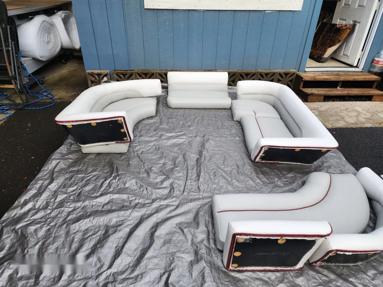 Full pontoon boat seating set reupholstered in white vinyl with red piping.