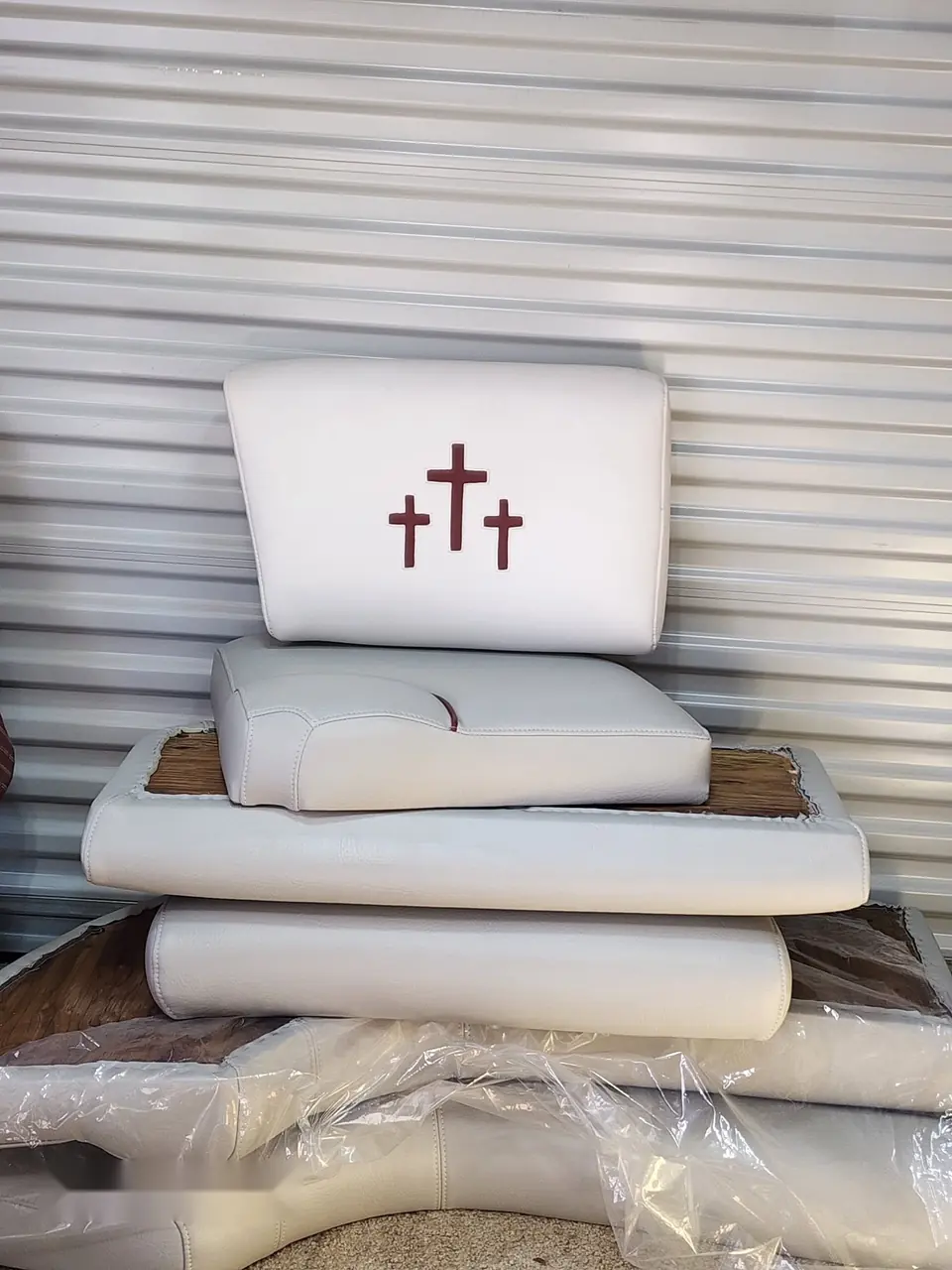 Stack of white marine cushions with an embroidered triple-cross detail.
