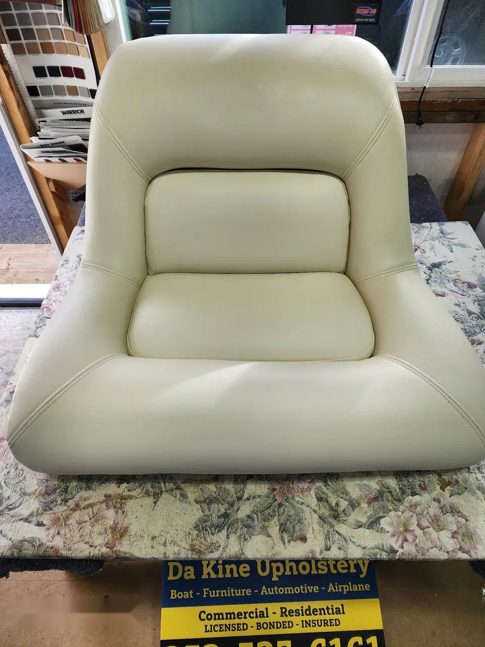 Boat captain's seat reupholstered in cream marine vinyl.